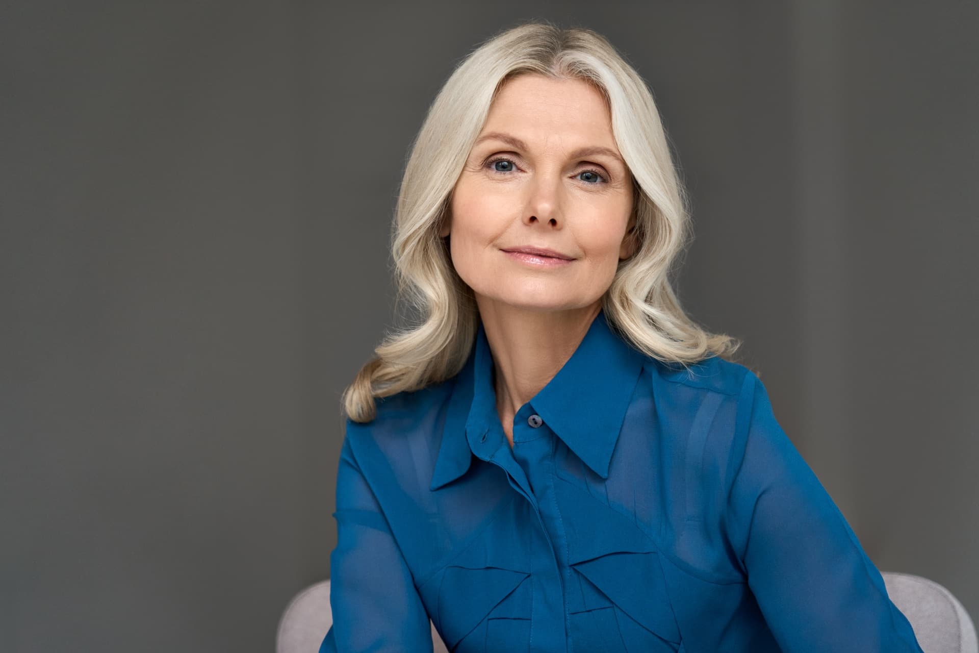 A woman with silver hair, composed and at ease.